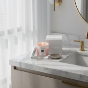 elenianna Milos Whispers of Love candle on a marble bathroom vanity, creating a luxury home spa and aromatherapy experience.