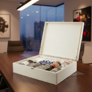 Elenianna luxury Greek gourmet food hamper in an open wooden crate, placed on a polished conference table in a modern corporate office with a city skyline view at dusk.
