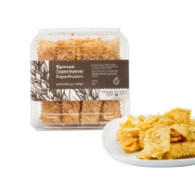 Simantiraki Cretan Xerotigana Bites with Sesame packaging next to a plate of crispy honey-dipped pastries.