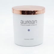 Close-up of the Aurean Golden Lumos luxury candle showing the high-shine rose gold metallic lid and "Greece’s Golden Ambiance" branding.
